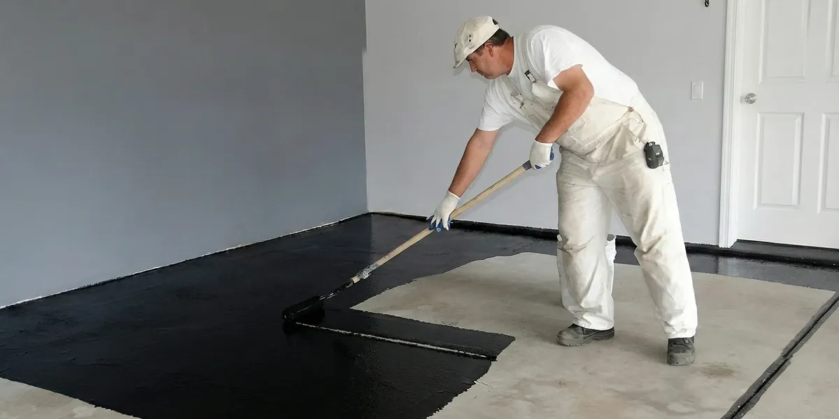 basement waterproofing professional applying waterproof coating to protect a basement floor in Charlotte, NC